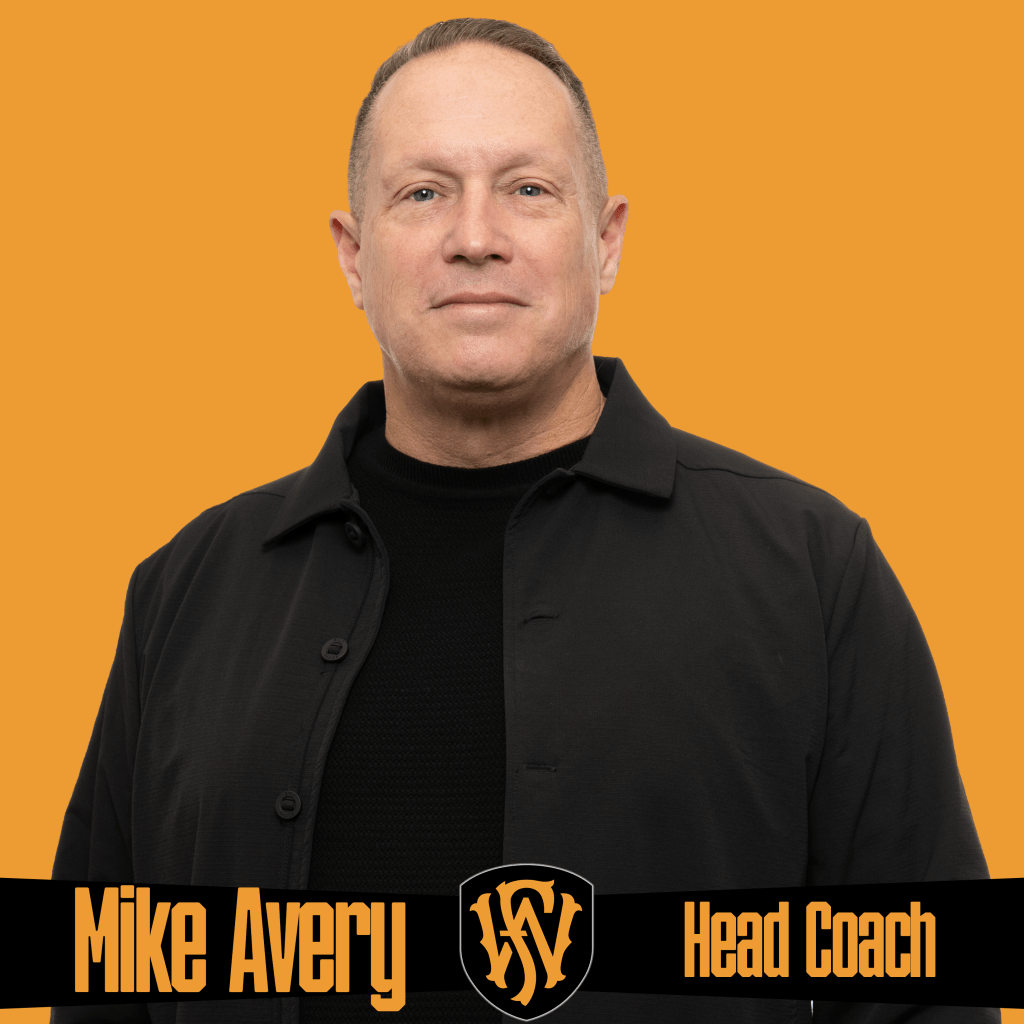 A man wearing a black jacket stands confidently against an orange background. The graphic features the Fort Wayne FC logo and text reading “Mike Avery | Head Coach.” Promotional image showcasing Fort Wayne FC’s head coach and team leadership.