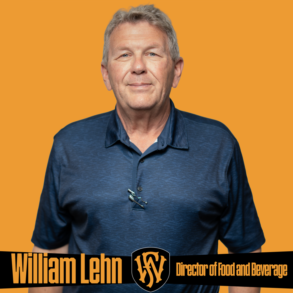A man wearing a navy blue collared shirt stands in front of an orange background. The graphic includes the Fort Wayne FC logo and text reading “William Lehn | Director of Food and Beverage.” Promotional image featuring Fort Wayne FC’s food and beverage operations leadership.